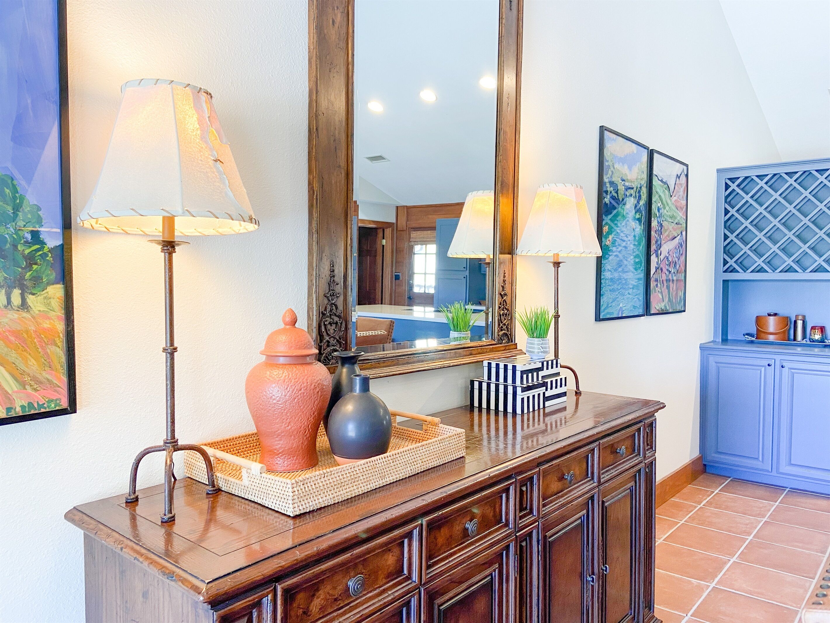 A wooden console table with two lamps, a mirror, and decorative items.