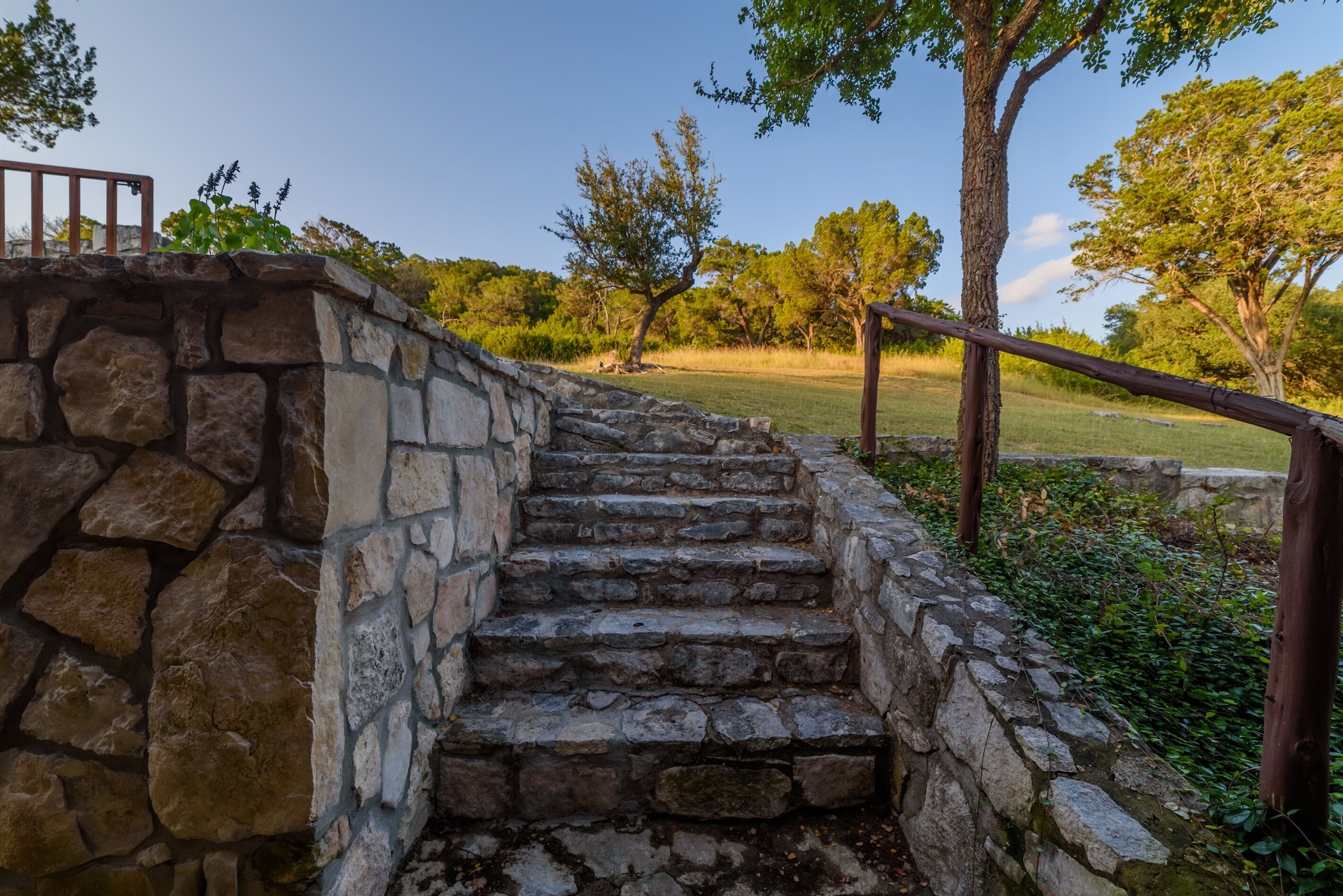A stone staircase leading up to a wooden deck with a metal railing.