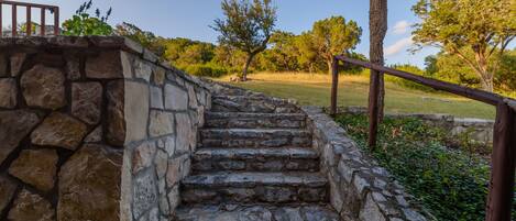 A stone staircase leading up to a wooden deck with a metal railing.