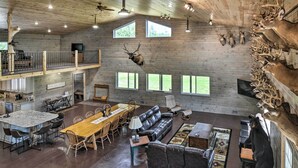 Un'ampia zona giorno con soffitto alto, travi in legno e un'area pranzo con un tavolo grande e sedie.