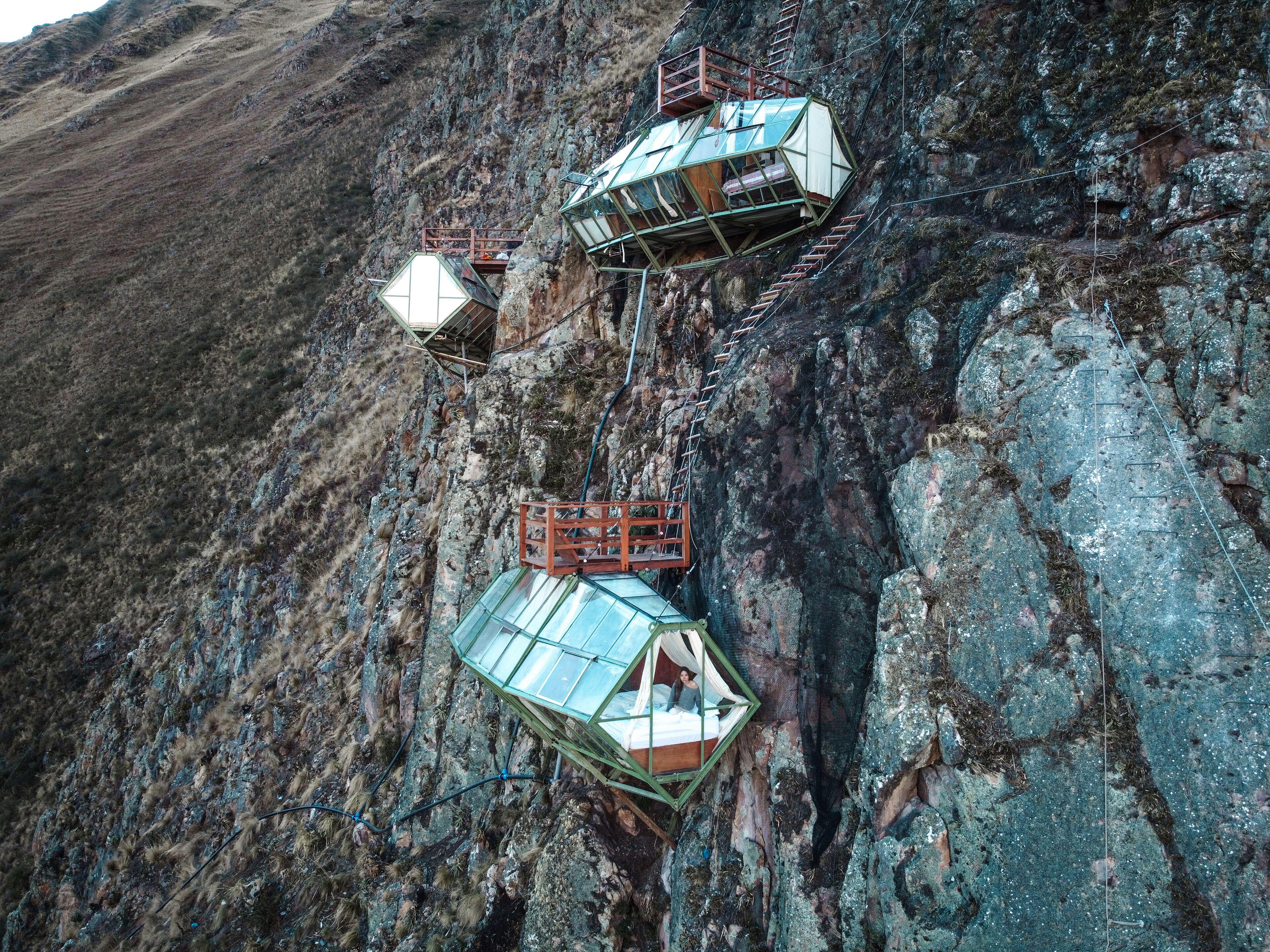 Three glass-domed structures attached to a rocky cliff.
