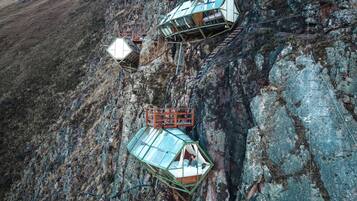Three glass-domed structures attached to a rocky cliff.