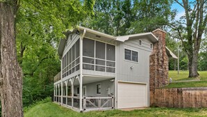 A two-story house with a large balcony, a garage, and a stone chimney.