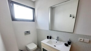 Pieni, siisti kylpyhuone, jossa on wc, pesuallas ja peili.