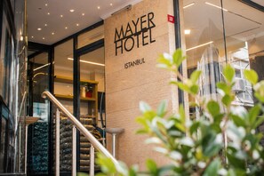 Exterior del Hotel Mayer en Estambul, con un diseño moderno que incluye puertas de vidrio y una escalera visible.