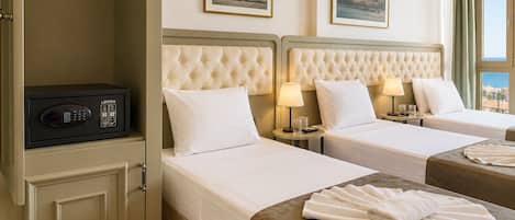 A hotel room with two beds, a minibar, and a view of the sea.