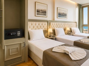 Habitación de hotel con dos camas, un minibar y vistas al mar.