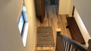 Unes escales de fusta amb barana, un tapís estampat al llindar i una finestra a l'esquerra.