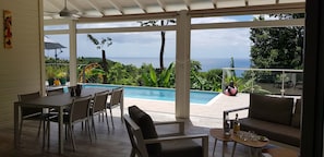 Un espace extérieur abrité comprenant une piscine, une table à manger et des sièges.
