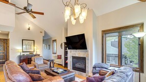 A spacious living room with leather sofas, a fireplace, a flat-screen TV, and a chandelier. - Rocky Mountain Retreat: 2 Mi to Beaver Creek! (Avon)
