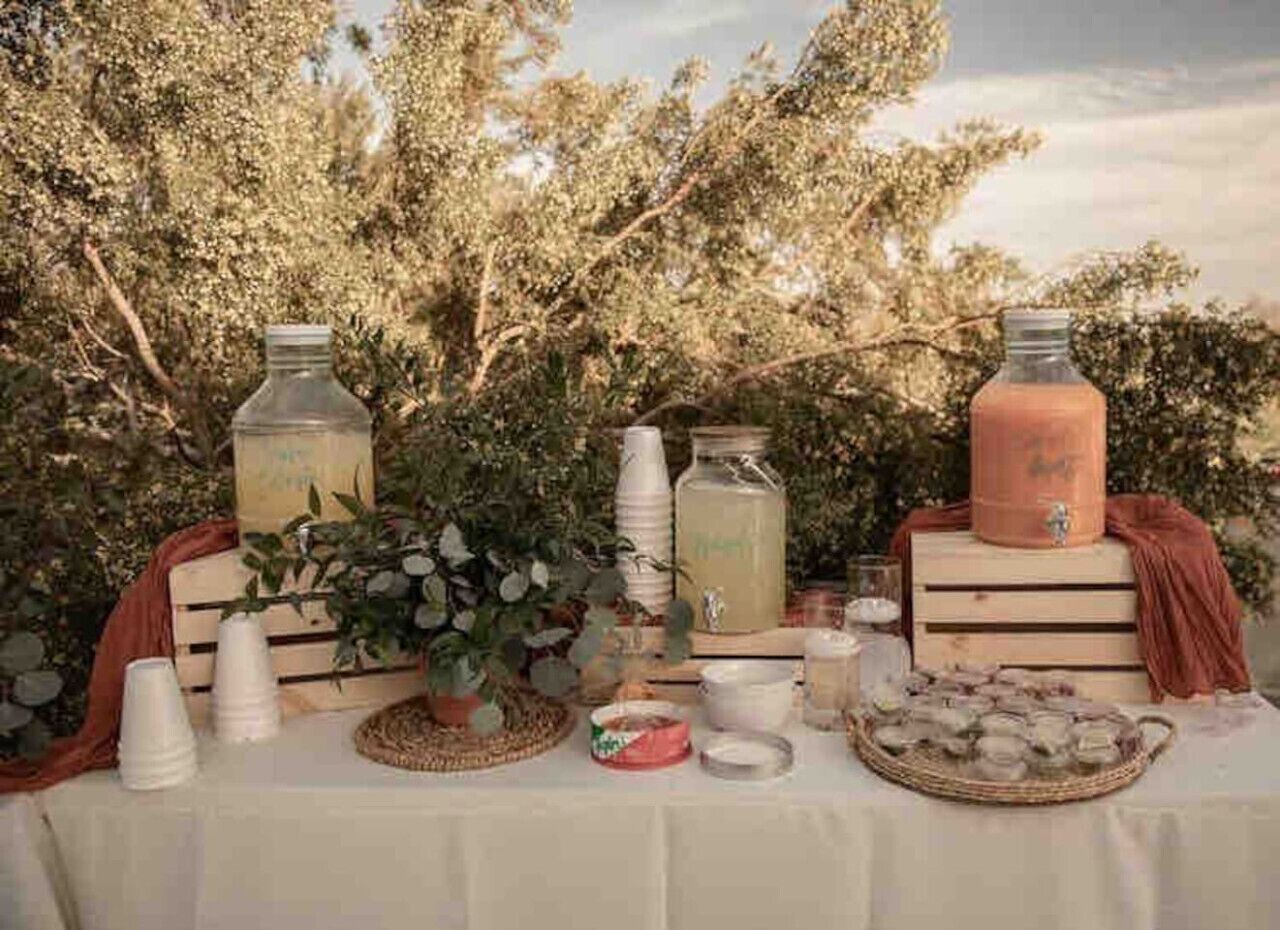 A table set outdoors with various items including bottles, cups, and a basket.