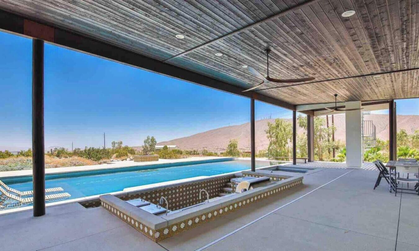 A covered outdoor swimming pool area with a view of a desert landscape.