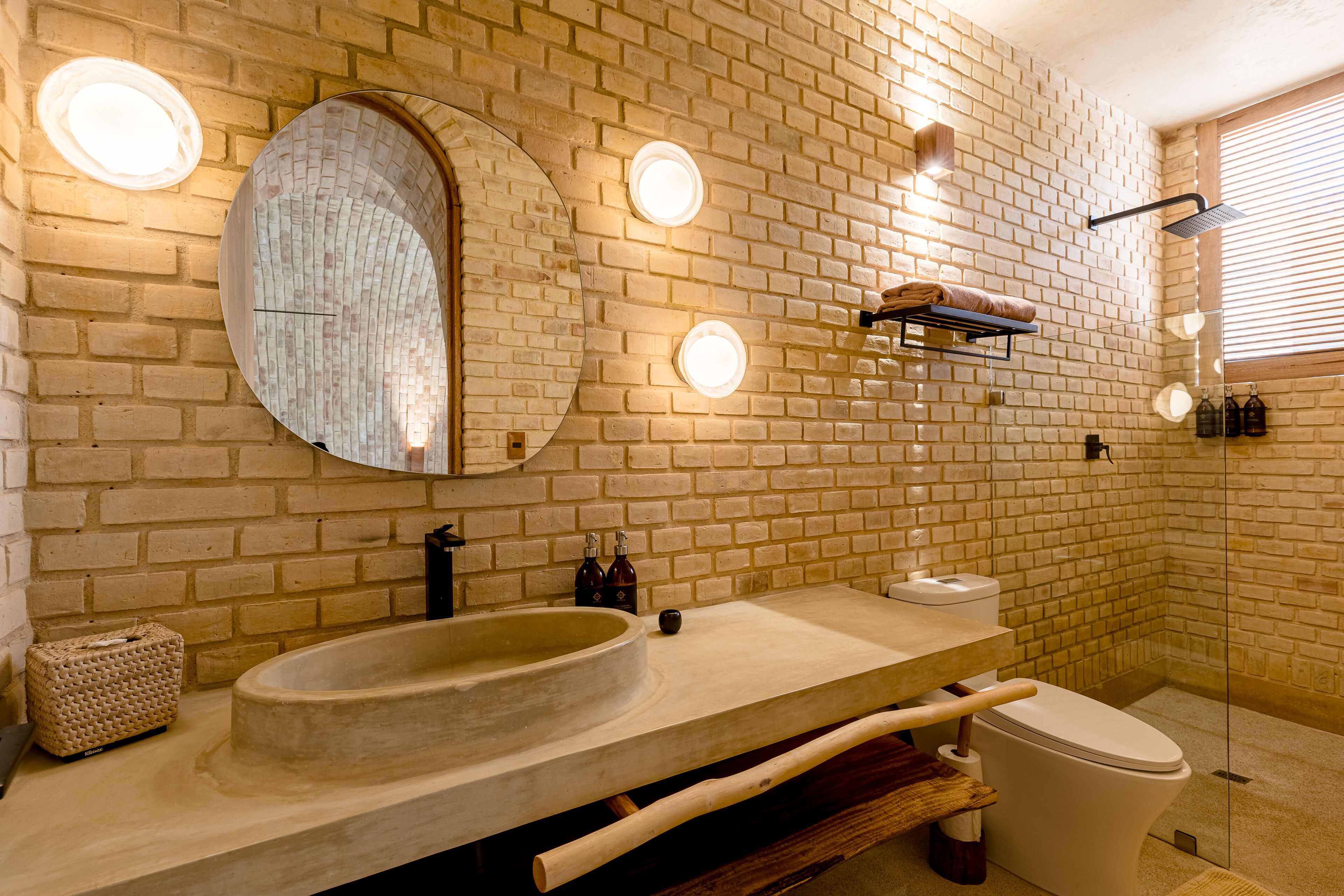 A bathroom with a large round sink, a toilet, and a shower area.