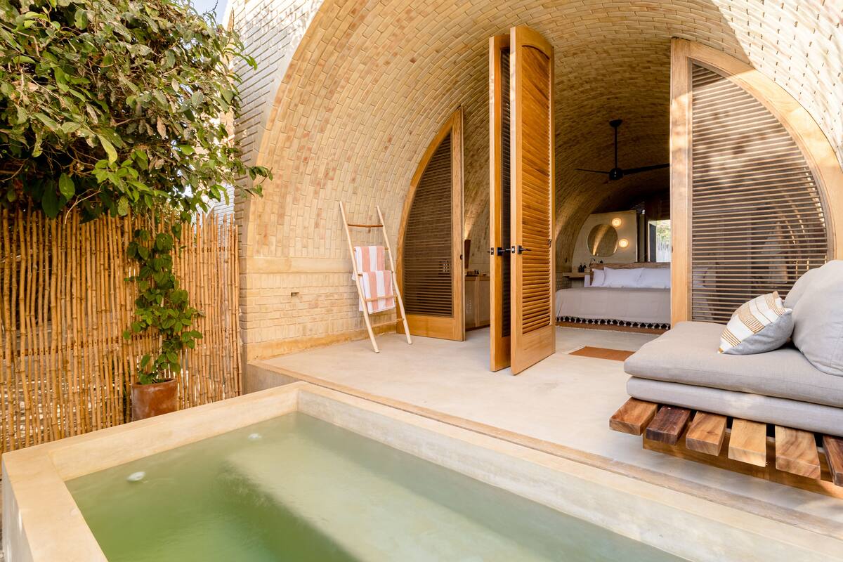 A spa area with a hot tub, wooden seating, and bamboo walls.