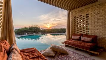 Une chambre moderne avec vue sur une piscine et sur le coucher de soleil.
