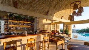 A bar area with wooden chairs and a pool view.
