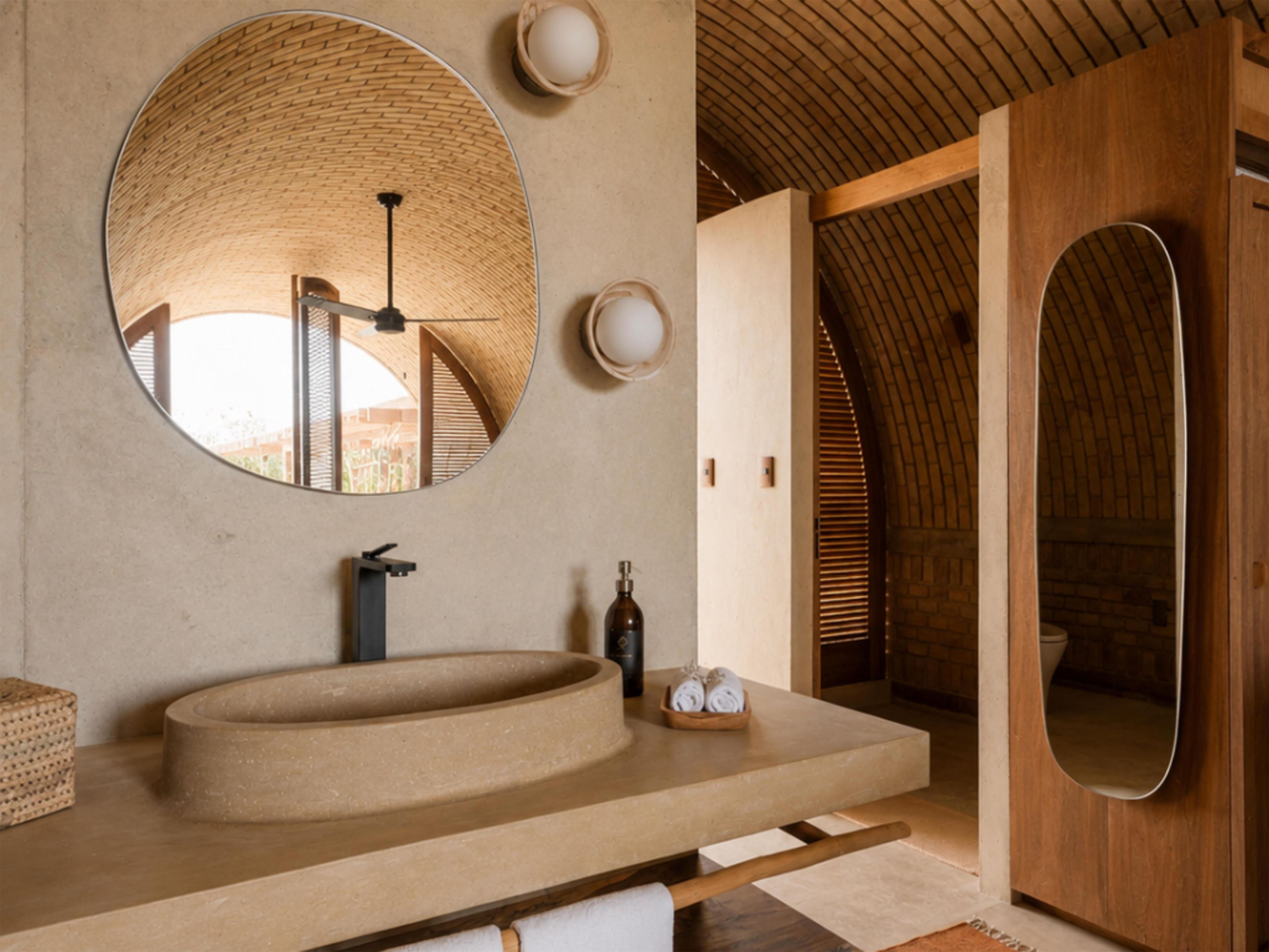 A bathroom with a round mirror, a sink, and a wooden ceiling.