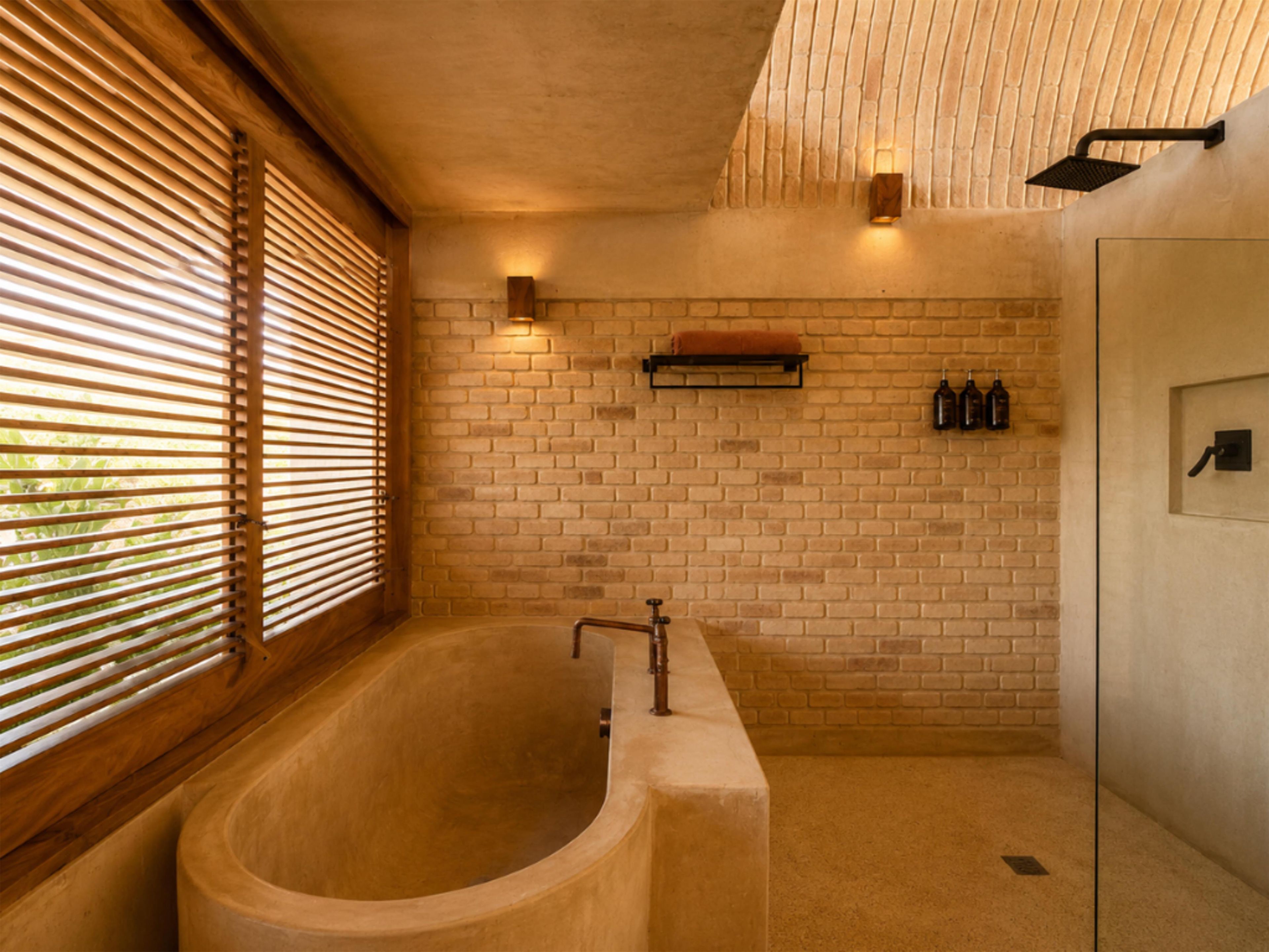 Ein modernes Badezimmer mit einer freistehenden Badewanne, einer Duschkabine aus Glas und einer Ziegelwand.