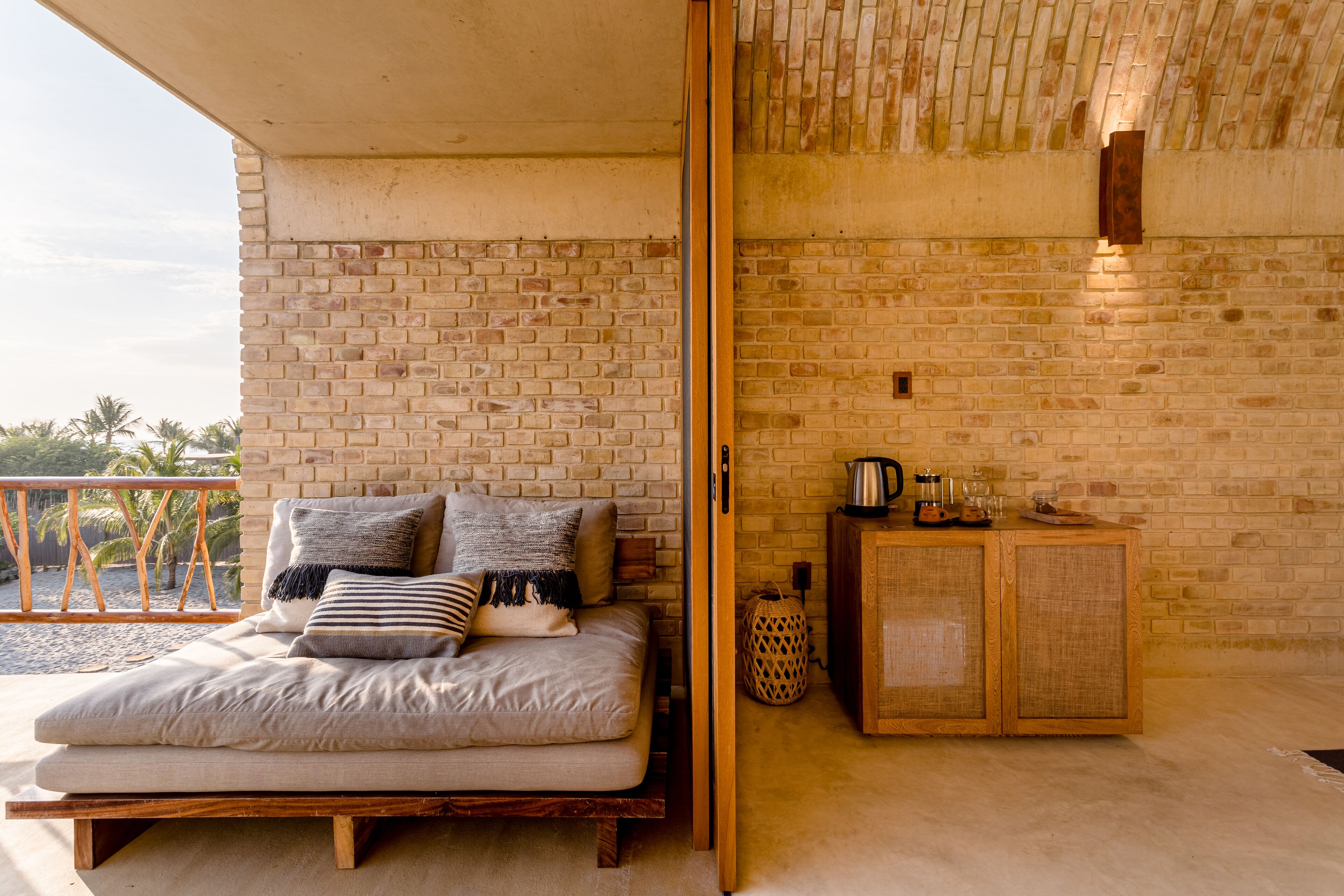 A room with a bed, a wooden cabinet, and a brick wall.