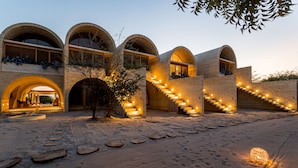 A modern building with arched windows and a series of steps leading to a covered entrance.