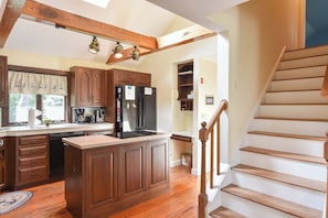 A kitchen with wooden cabinets, a central island, a stove, and a refrigerator.
