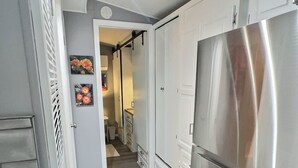 Een moderne keuken met witte kastjes, een roestvrijstalen koelkast en een houten vloer.