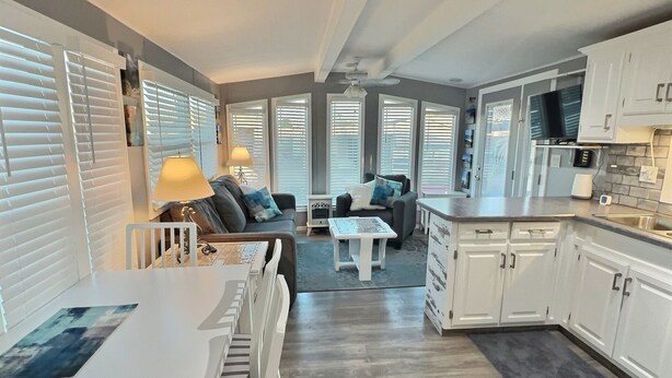 Een moderne keuken met witte kastjes, een eethoek met tafel en stoelen, en een woonkamer met een bank en salontafel.