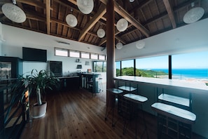 Una cocina moderna con vigas de madera, una barra con taburetes y ventanas amplias con vistas panorámicas.