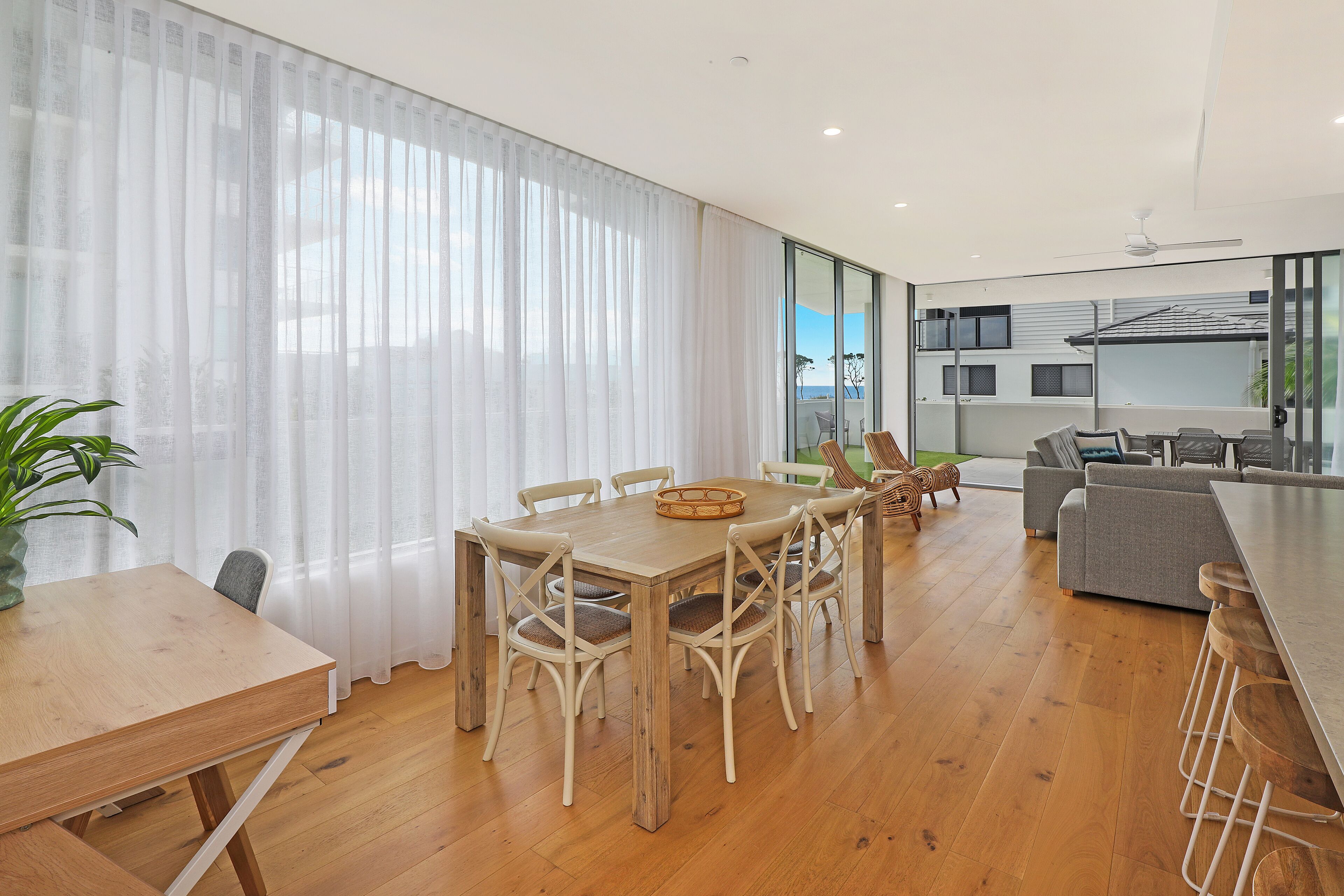 A modern living room with a wooden dining table, chairs, and a sofa.