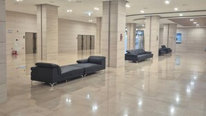 A spacious lobby with a polished tile floor, several black sofas, and a modern ceiling with recessed lighting. - Landmark Stay in Songdo (Incheon)