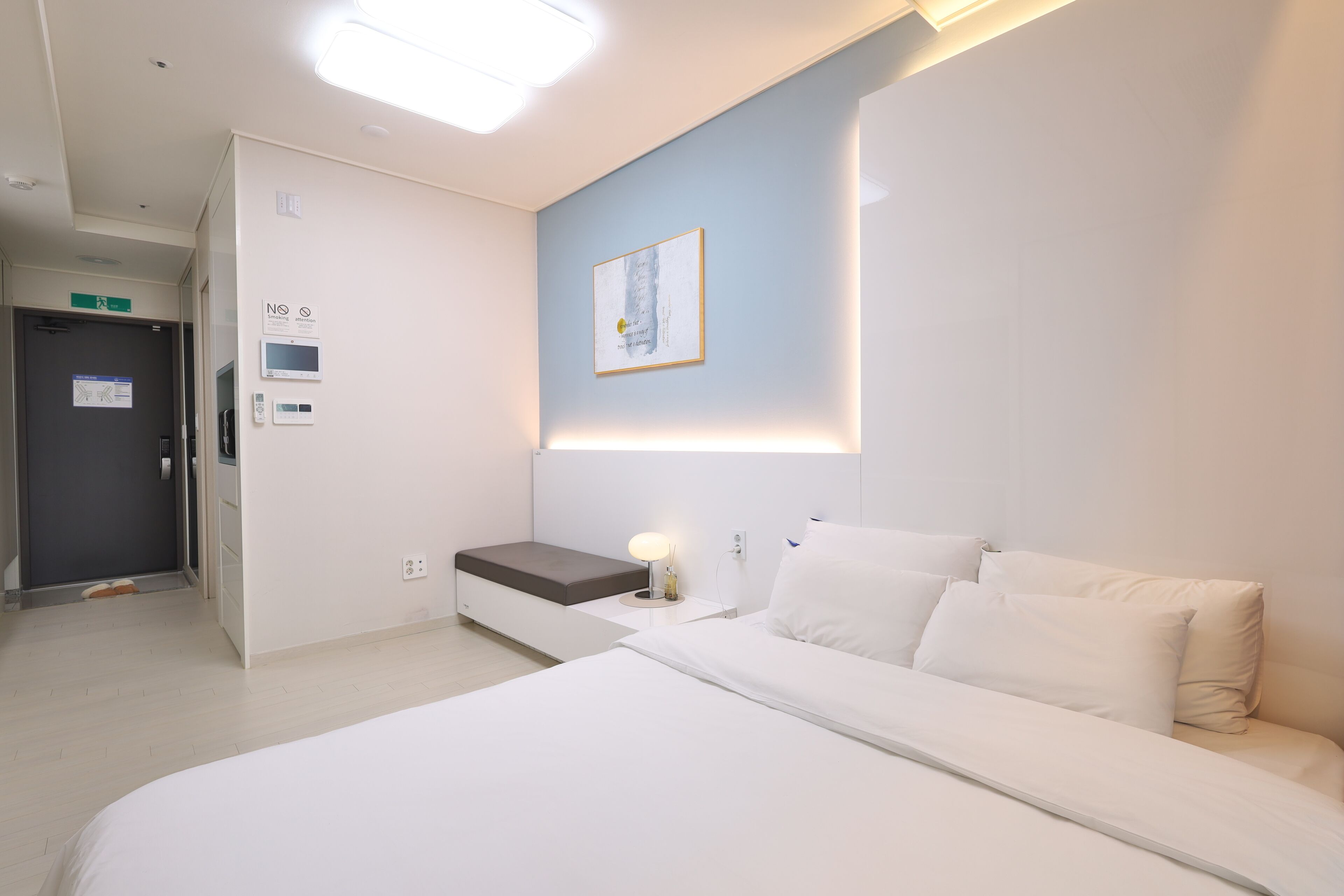 A hotel room with a bed, bedside table, and a wall-mounted light fixture.