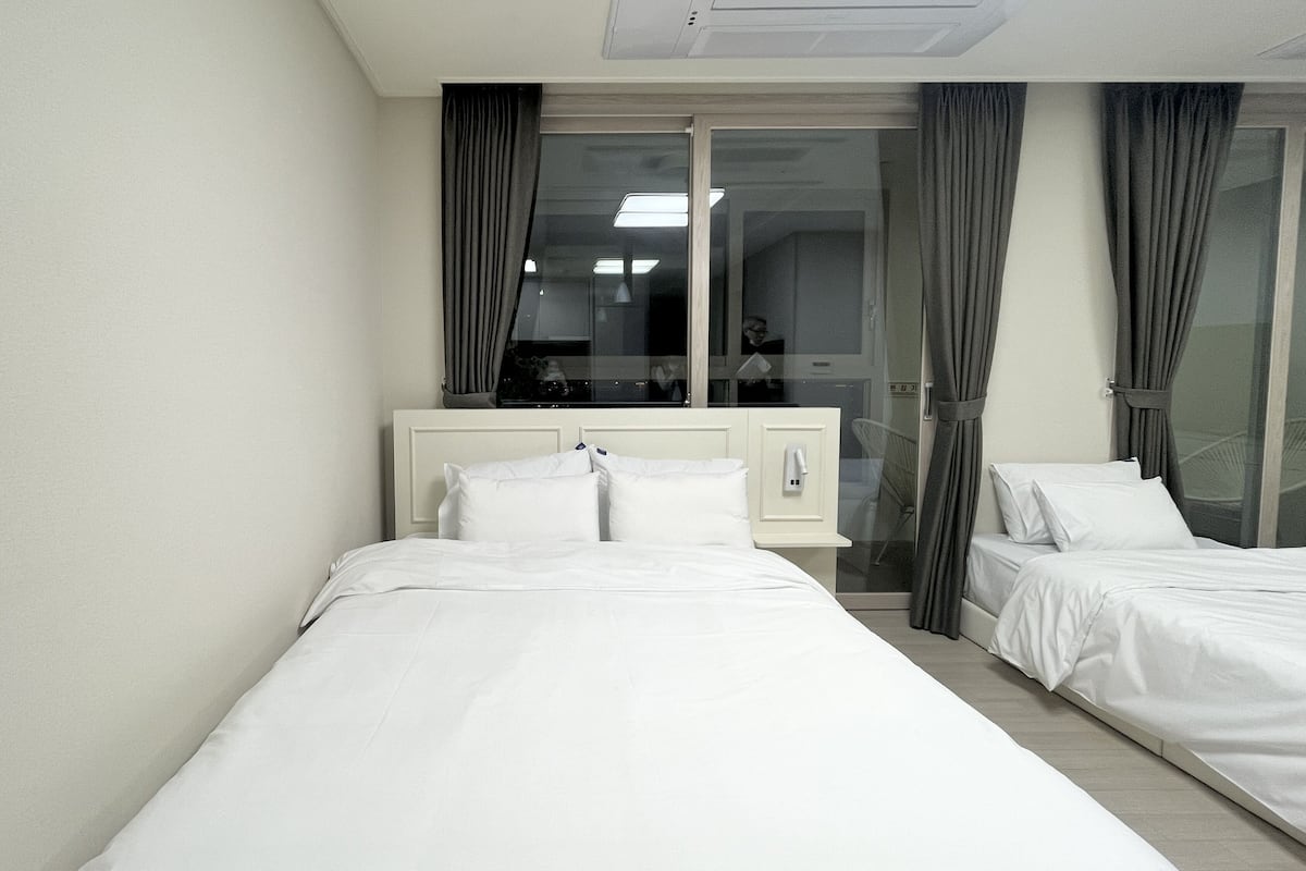 Ein Hotelzimmer mit zwei Betten, einem großen Fenster und Blick nach außen.