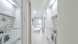 A modern laundry room with two washing machines, a sink, and a window providing natural light. - Landmark Stay in Songdo (Incheon)