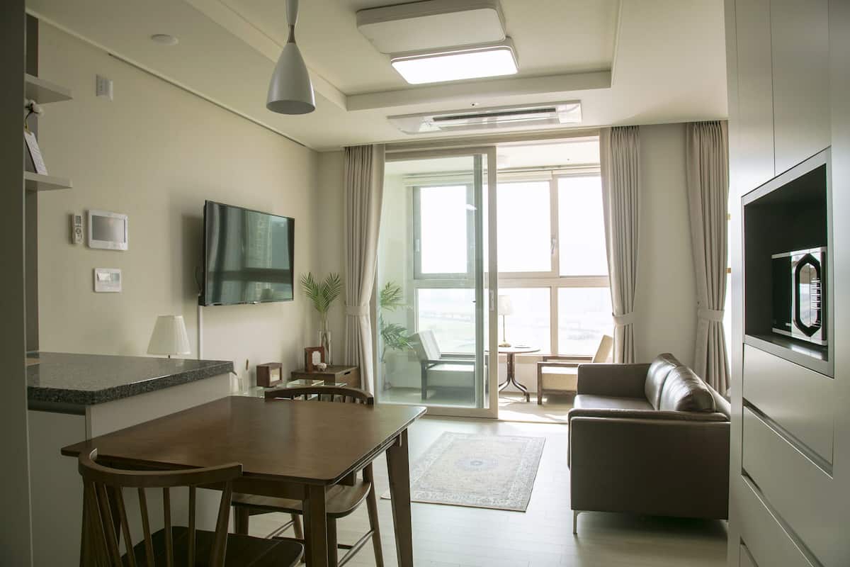 Ein modernes Wohnzimmer mit Essbereich, einem Flachbildfernseher und einer Glastür zum Balkon.