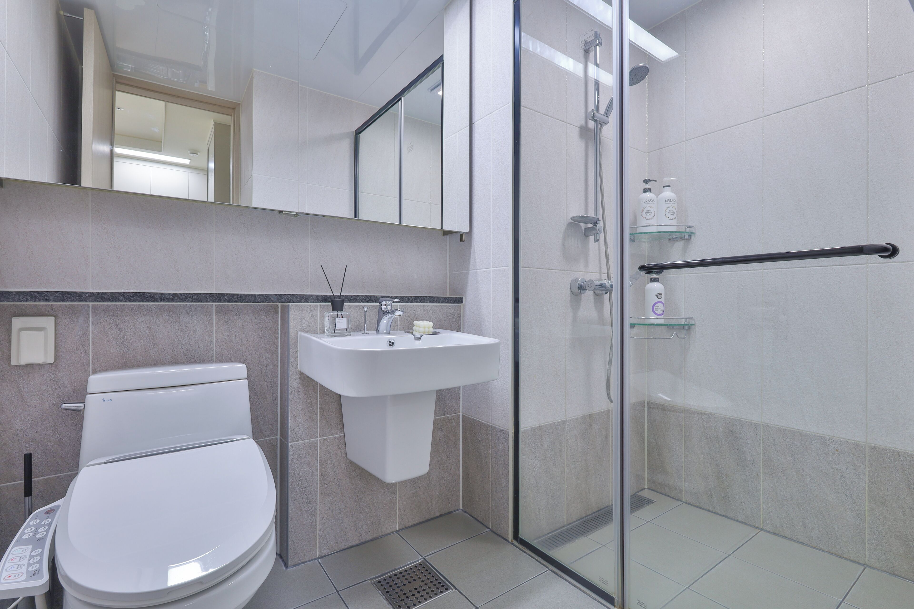 Ein modernes Badezimmer mit Toilette, Waschbecken und Duschkabine aus Glas.
