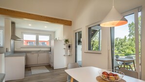 A modern kitchen with a dining area, large windows, and a view of the outdoors. - Attic Apartment ‘Marla’ with Wi-Fi & Balcony (Eriskirch)