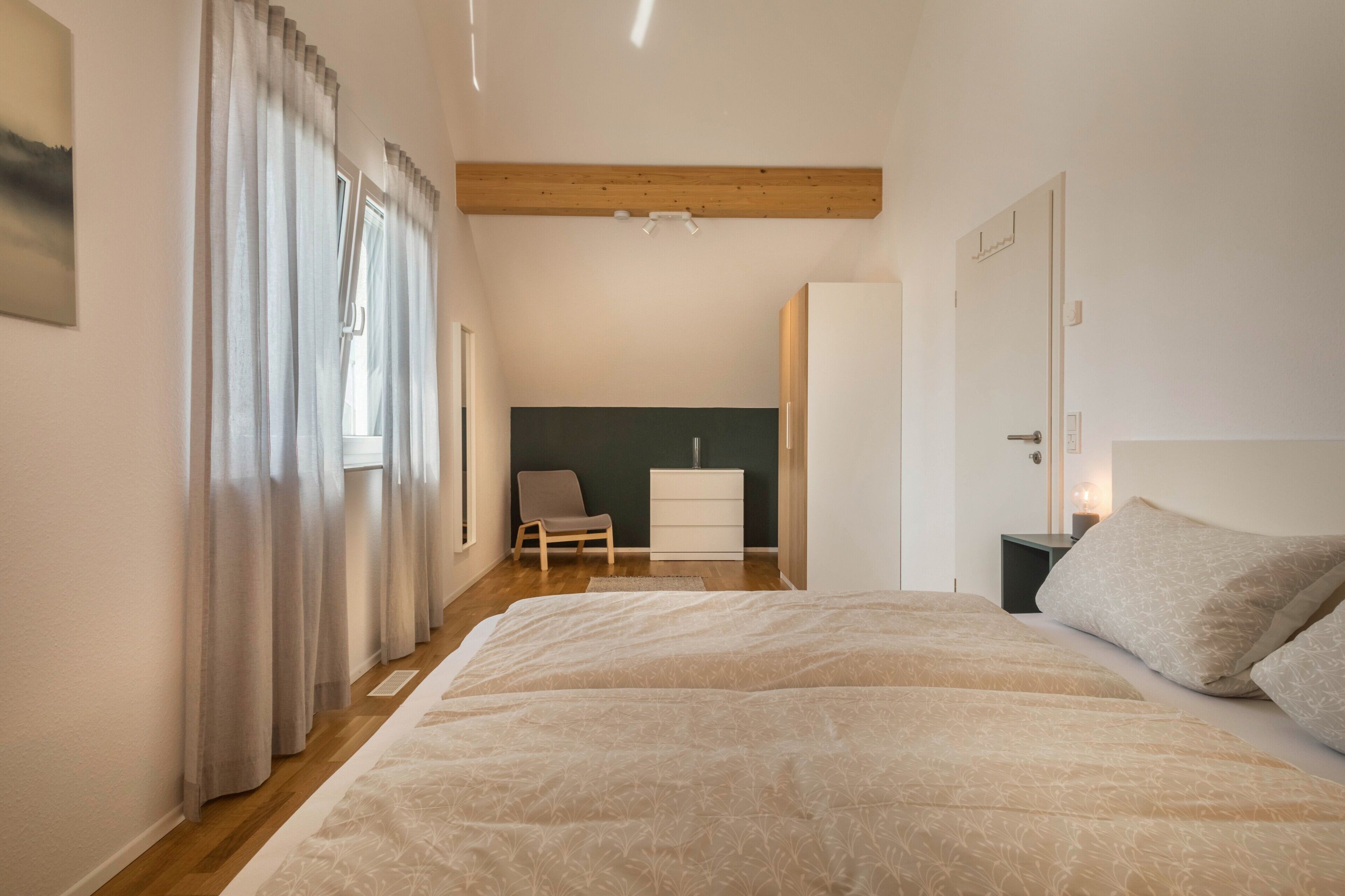 Quarto com uma cama grande, uma cadeira, cômoda e armário.