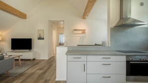 A modern kitchen with white cabinetry, a built-in stove, and a large island with a countertop. - Attic Apartment ‘Marla’ with Wi-Fi & Balcony (Eriskirch)