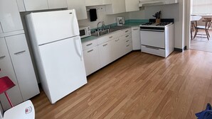 Cuina amb armaris blancs, un frigorífic, una placa de cocció i un microones.