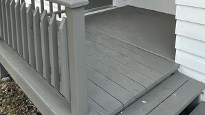Una casa blanca amb una porta davantera grisosa i una finestra petita a la part superior.