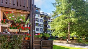 A multi-story building with balconies, potted plants, and a well-maintained lawn.