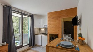 A compact kitchen with a dining area, a TV mounted on the wall, and a view of the outdoors.