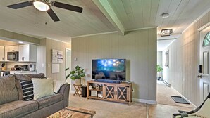 A living room with a sofa, coffee table, TV, and a wooden entertainment center. - Deck & Gas Grill: Modern East Stroudsburg Home! (East Stroudsburg)