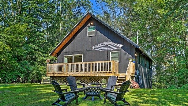 A cabin with a deck, a fire pit, and Adirondack chairs. - Deck & Gas Grill: Modern East Stroudsburg Home! (East Stroudsburg)