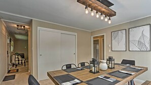 A dining area with a long wooden table, black and gray placemats, black chairs, and a ceiling light fixture. - Deck & Gas Grill: Modern East Stroudsburg Home! (East Stroudsburg)