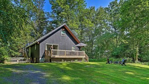 A cabin with a wooden deck and a covered outdoor seating area. - Deck & Gas Grill: Modern East Stroudsburg Home! (East Stroudsburg)