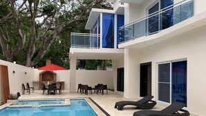 A modern outdoor pool area with a barbecue, lounge chairs, and a covered seating area. - New lovely house at walking distance from beautiful Sosua beach.  (Sosúa)