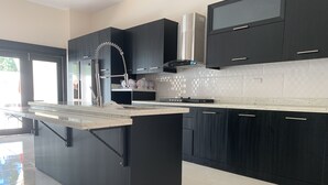 A modern kitchen with black cabinets, a stainless steel sink, and a large island. - New lovely house at walking distance from beautiful Sosua beach.  (Sosúa)