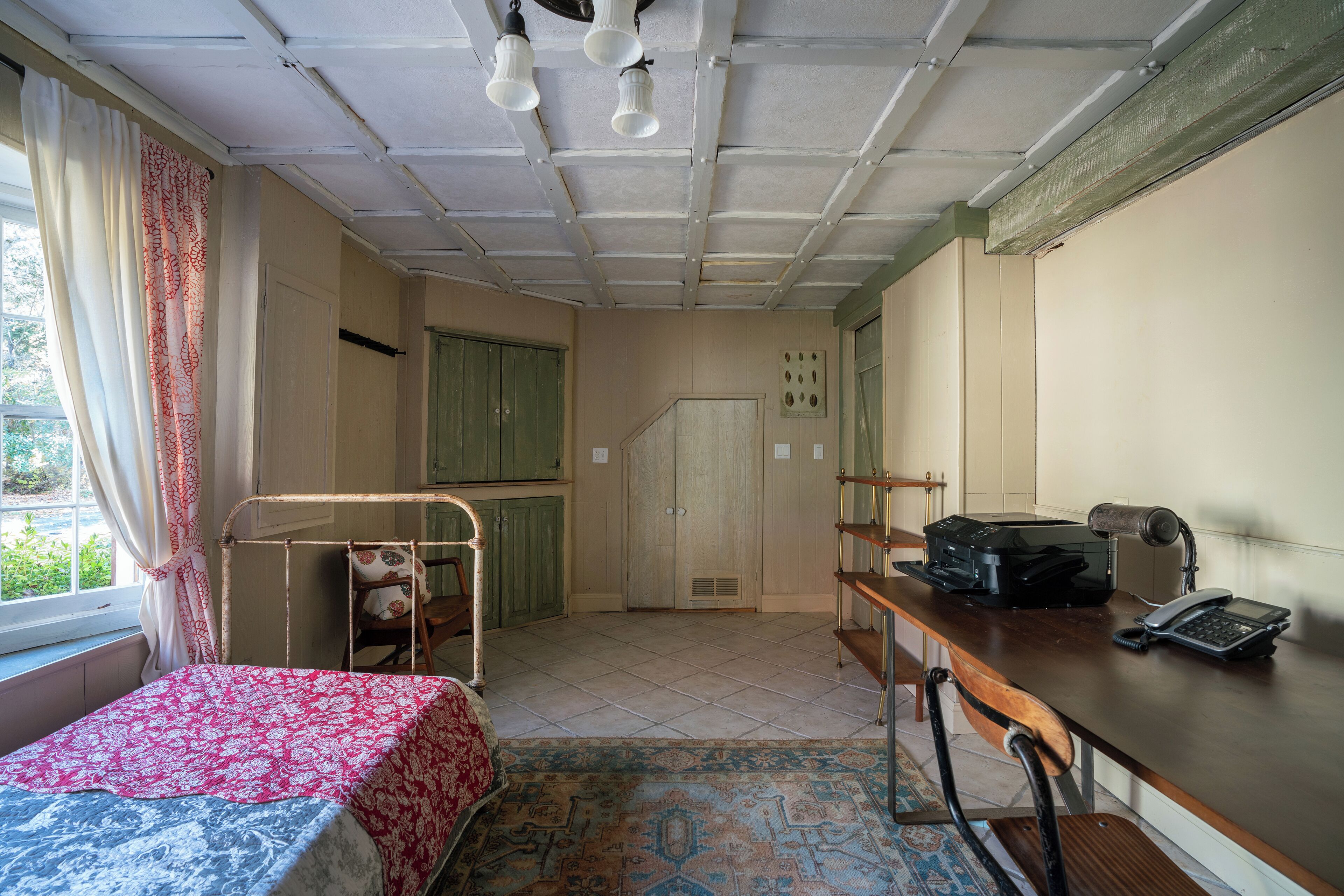 A room with a bed, desk, and kitchenette.