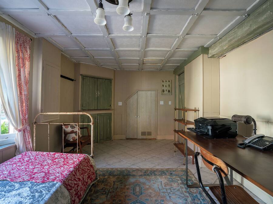 A room with a bed, desk, and kitchenette.